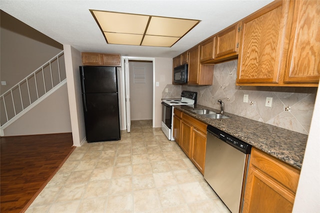 kitchen featuring black appliances, dark stone countertops, and sink