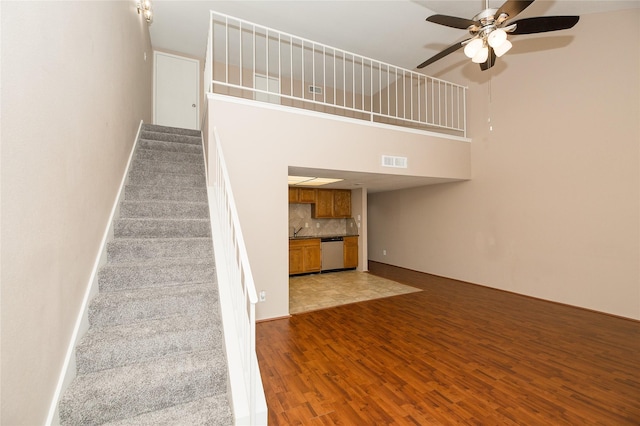 stairs with hardwood / wood-style flooring, ceiling fan, and a high ceiling