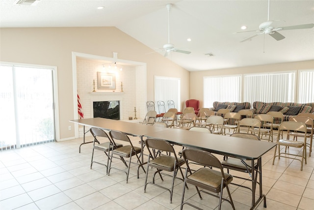 tiled dining space with ceiling fan, vaulted ceiling, and a brick fireplace