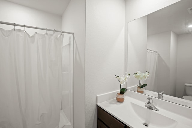 bathroom featuring vanity, curtained shower, and toilet