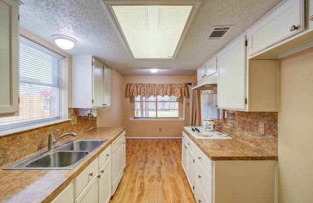 kitchen featuring backsplash, white cabinets, sink, light hardwood / wood-style flooring, and a textured ceiling