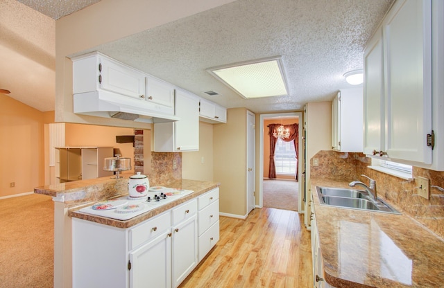 kitchen with white cabinets, light wood-type flooring, sink, and a textured ceiling