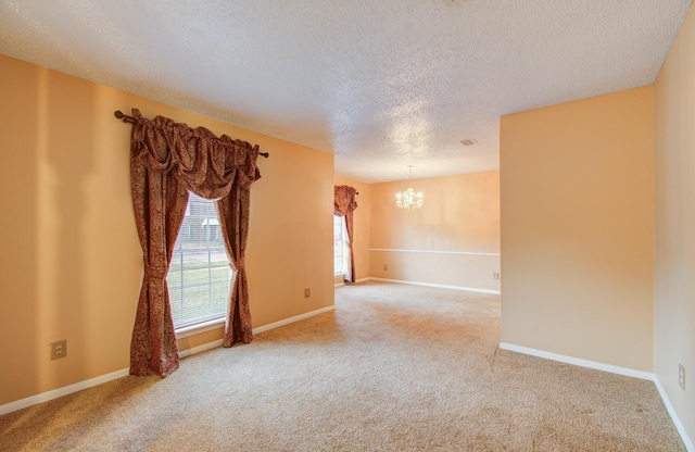 carpeted empty room with a textured ceiling and an inviting chandelier