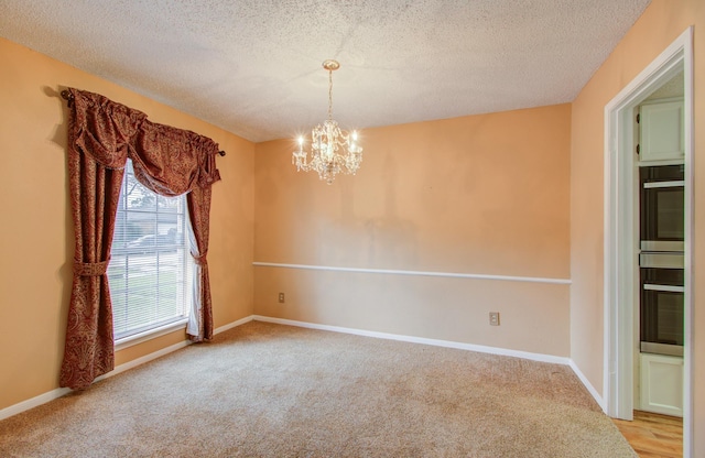 carpeted spare room with a chandelier and a textured ceiling