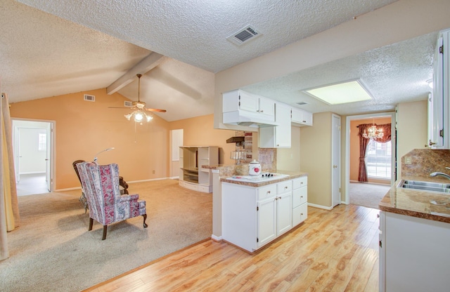 kitchen featuring white cabinets, vaulted ceiling with beams, light hardwood / wood-style floors, and sink