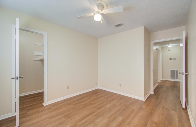 empty room with ceiling fan, a textured ceiling, and light hardwood / wood-style flooring