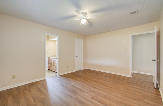 unfurnished bedroom with ensuite bath, ceiling fan, light hardwood / wood-style floors, and a textured ceiling