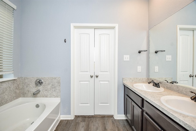 bathroom with hardwood / wood-style floors, vanity, and a tub to relax in