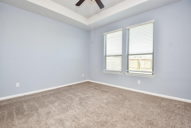 carpeted spare room featuring ceiling fan and a raised ceiling