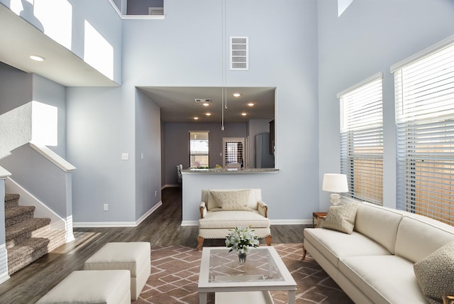 living room featuring a towering ceiling and dark wood-type flooring