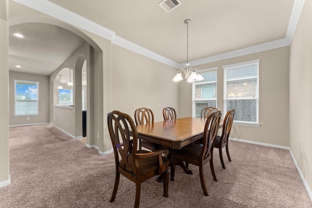 carpeted dining area with a chandelier and ornamental molding