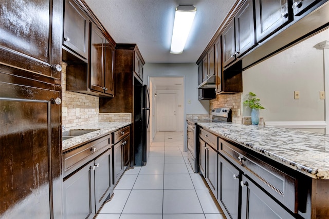 kitchen with tasteful backsplash, black fridge, light stone counters, dark brown cabinets, and stainless steel range with electric cooktop