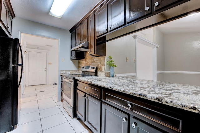 kitchen featuring light stone countertops, tasteful backsplash, black fridge, dark brown cabinets, and stainless steel electric stove