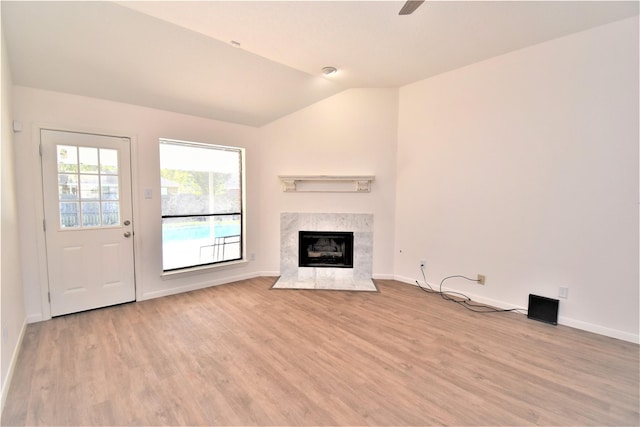 unfurnished living room with light hardwood / wood-style flooring, a high end fireplace, and vaulted ceiling