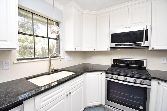 kitchen with appliances with stainless steel finishes, dark stone counters, sink, white cabinets, and hanging light fixtures