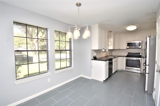 kitchen with hanging light fixtures, white cabinets, stainless steel appliances, and sink