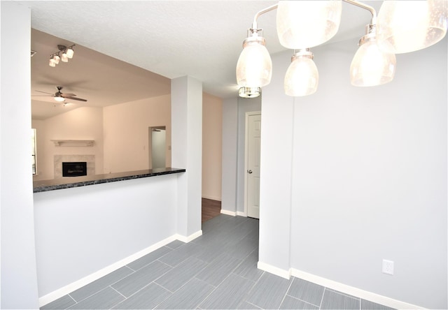 kitchen featuring a tile fireplace, ceiling fan, and lofted ceiling