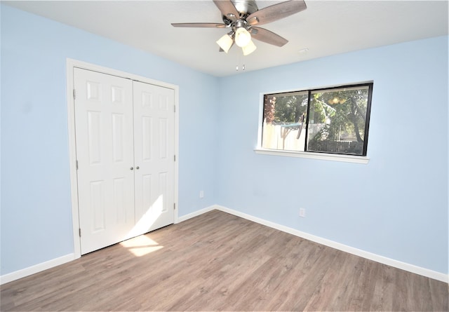 unfurnished bedroom with ceiling fan, light wood-type flooring, and a closet