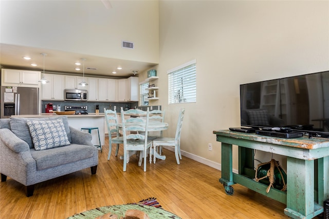 living room with light hardwood / wood-style floors and a high ceiling