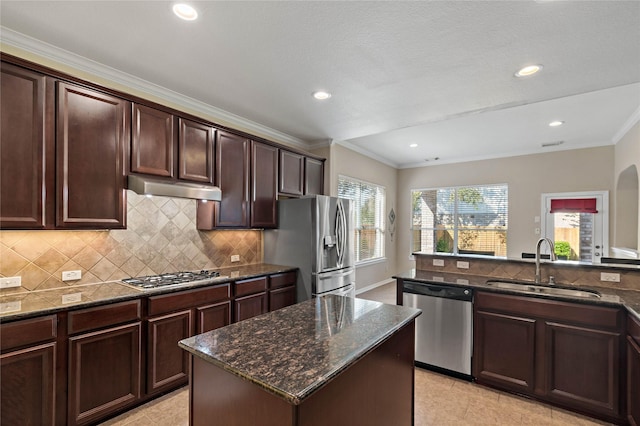 kitchen featuring sink, stainless steel appliances, dark stone counters, decorative backsplash, and a kitchen island