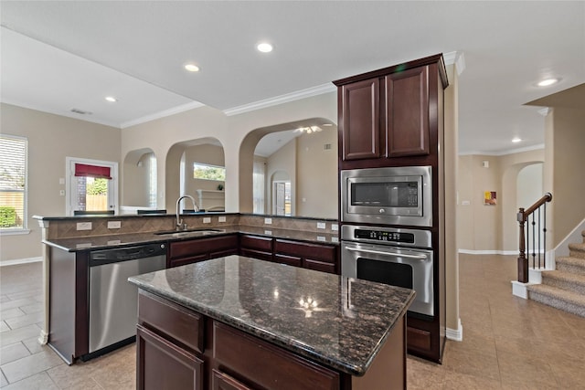 kitchen with dark stone countertops, sink, a center island, and stainless steel appliances