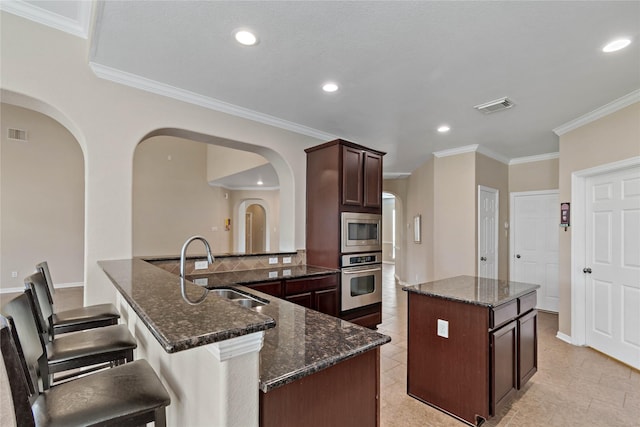 kitchen featuring appliances with stainless steel finishes, a center island, dark stone countertops, and sink