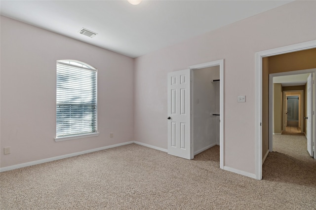 unfurnished bedroom with light carpet and a spacious closet