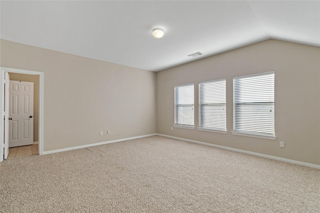 carpeted spare room with vaulted ceiling