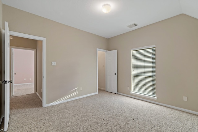 carpeted empty room featuring vaulted ceiling