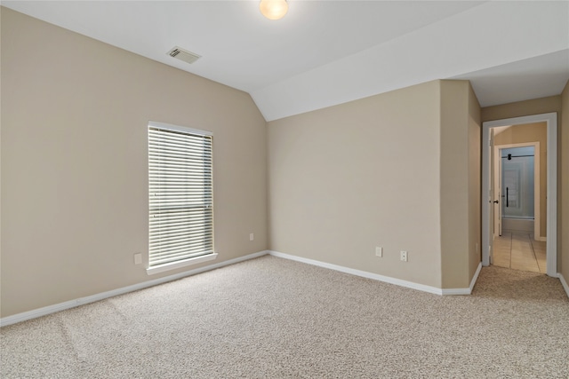 carpeted spare room featuring lofted ceiling