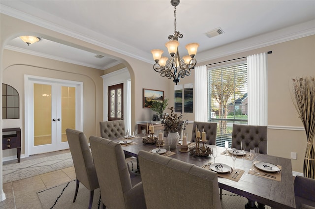 tiled dining room featuring crown molding, french doors, and a chandelier