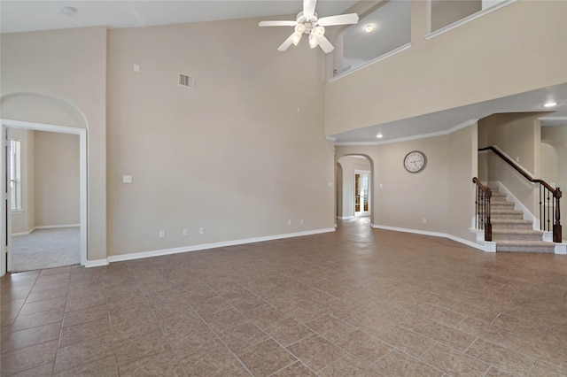 unfurnished living room featuring tile patterned flooring, ceiling fan, and a towering ceiling