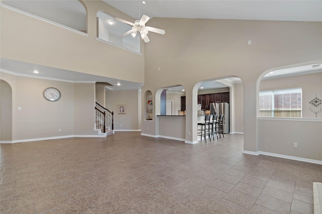 unfurnished living room featuring ceiling fan, a high ceiling, and ornamental molding