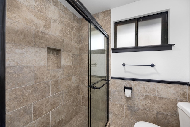 bathroom featuring walk in shower, tile walls, and toilet