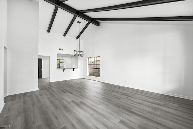 unfurnished living room with beamed ceiling, wood-type flooring, an inviting chandelier, and high vaulted ceiling