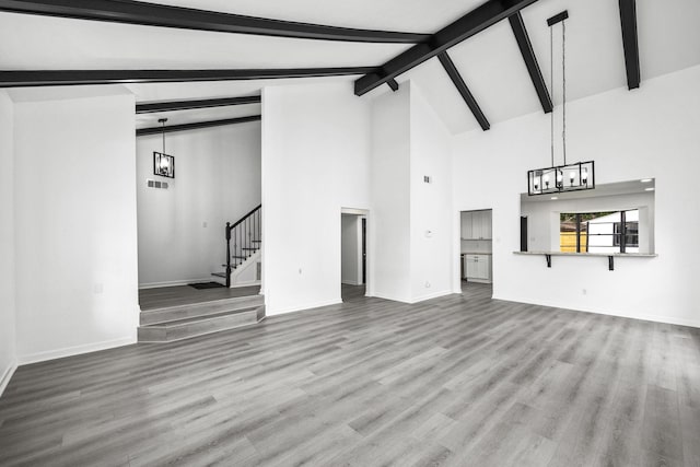 unfurnished living room with beamed ceiling, a notable chandelier, wood-type flooring, and high vaulted ceiling