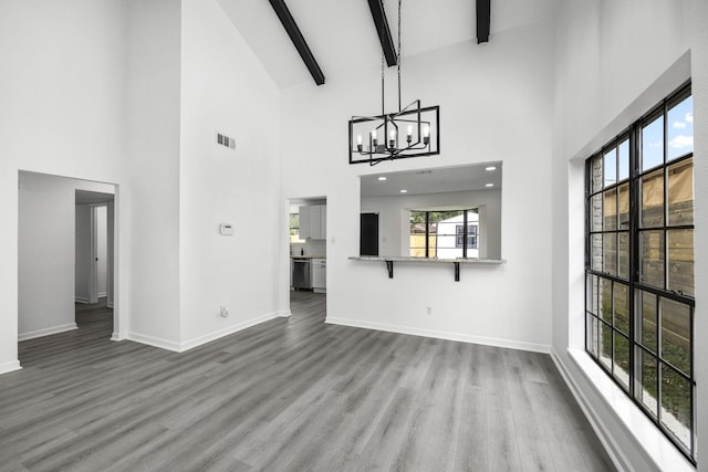 unfurnished living room featuring beamed ceiling, hardwood / wood-style floors, an inviting chandelier, and high vaulted ceiling