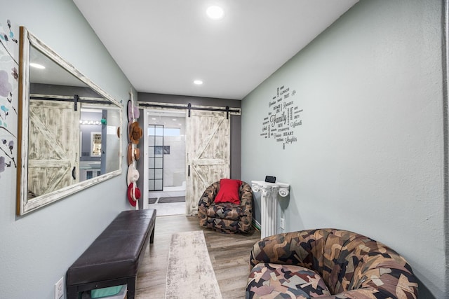 hallway with a barn door, hardwood / wood-style flooring, and radiator