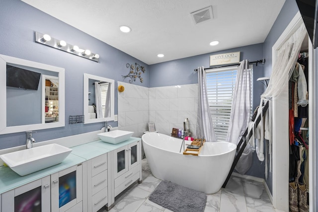 bathroom featuring vanity, a tub, and tile walls