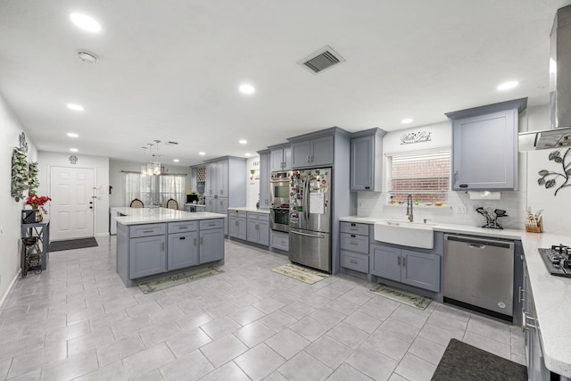 kitchen with gray cabinetry, hanging light fixtures, stainless steel appliances, and sink