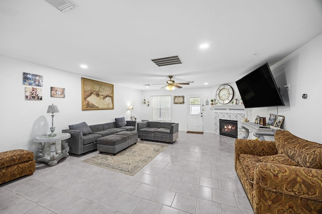 living room featuring a tiled fireplace and ceiling fan