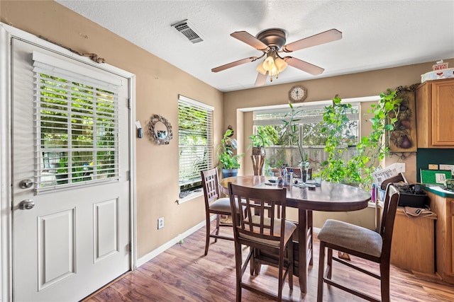 dining room with ceiling fan, light hardwood / wood-style floors, and a textured ceiling