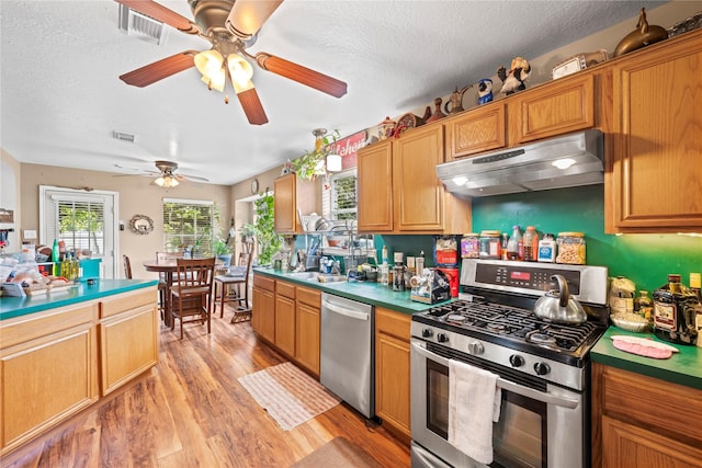 kitchen with sink, ceiling fan, a textured ceiling, appliances with stainless steel finishes, and light hardwood / wood-style floors