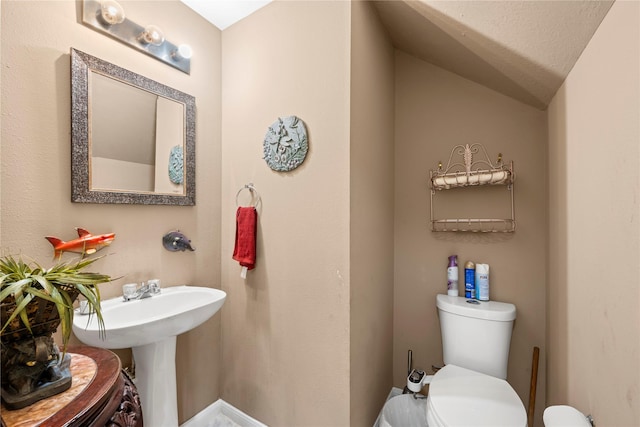 bathroom featuring vaulted ceiling and toilet