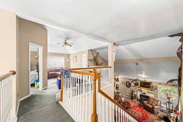 hall featuring a textured ceiling, carpet floors, and lofted ceiling