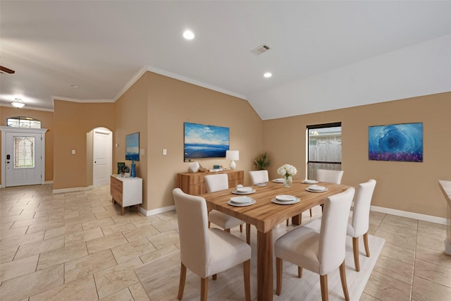 dining room featuring light tile patterned flooring, a healthy amount of sunlight, vaulted ceiling, and ornamental molding