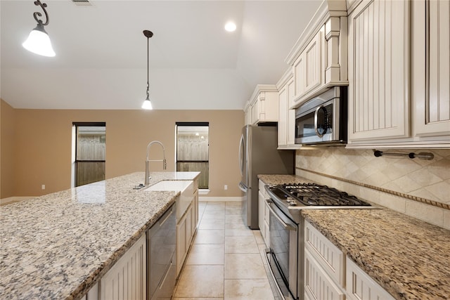 kitchen featuring tasteful backsplash, cream cabinets, pendant lighting, and appliances with stainless steel finishes