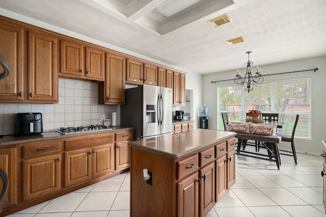 kitchen with a center island, a notable chandelier, decorative light fixtures, light tile patterned floors, and appliances with stainless steel finishes