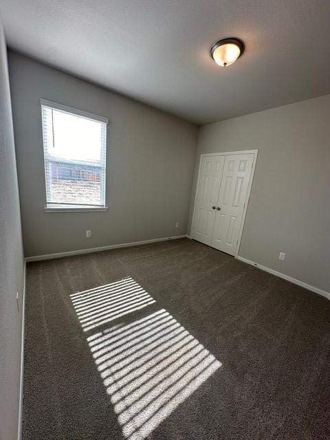 unfurnished room featuring dark carpet