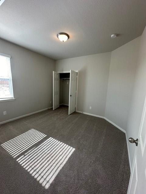 unfurnished bedroom with a closet and dark carpet